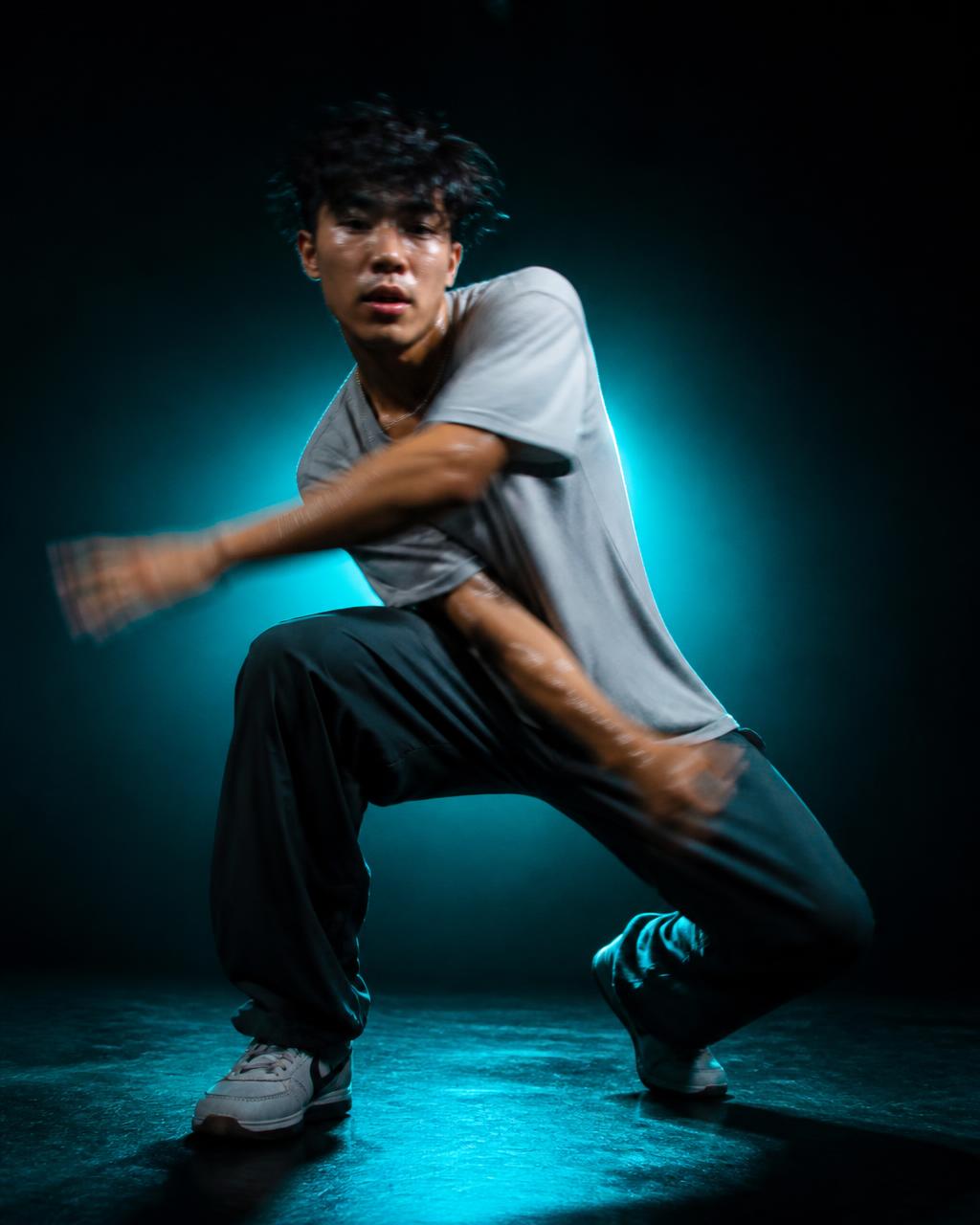 A hip-hop dancer holding a powerful freeze in a dark studio